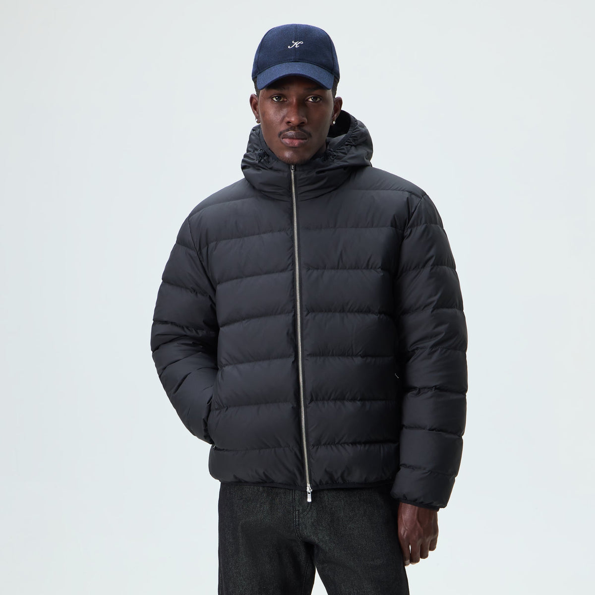 Man wearing black Kith Matte Stretch Taffeta Cameron puffer jacket with a cap, front view