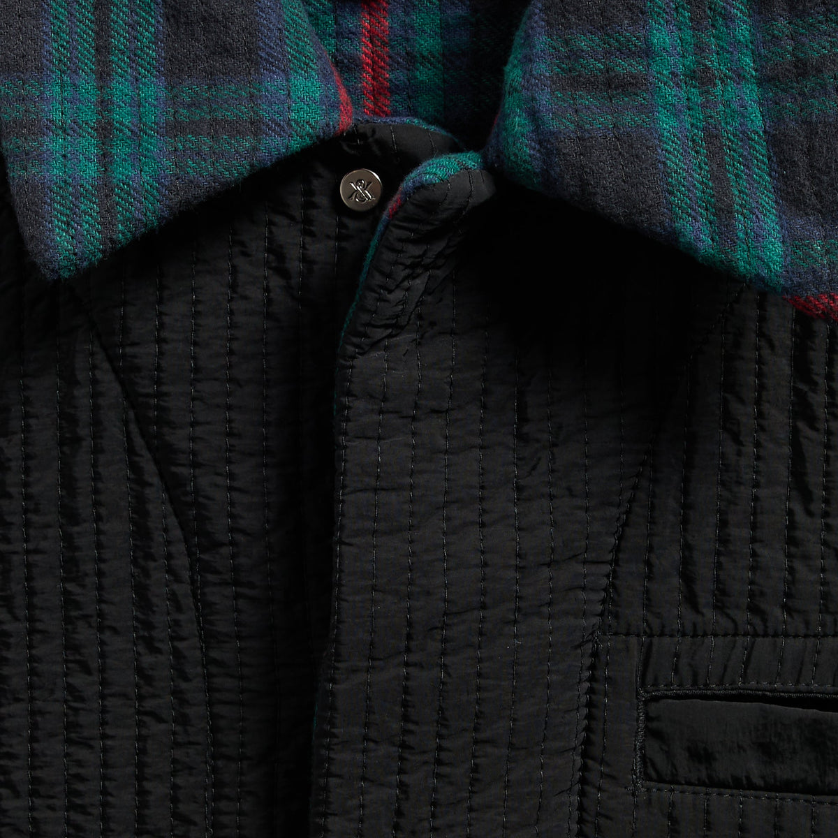 Close-up of the snap placket, plaid flannel and black quilting on the boxy collared overshirt